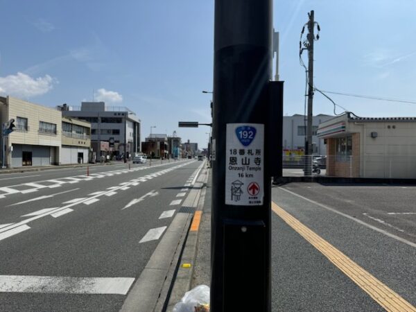 A highway road surface with marker pointing way to another temple.