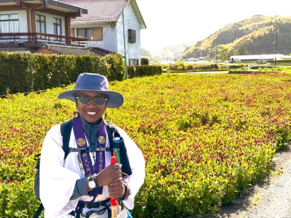 Pilgrim in front of field of red flowers.